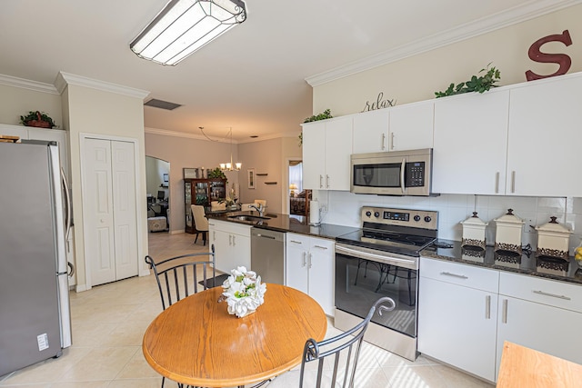 590 NW Cortina Ln, Port Saint Lucie, FL 34986 - kitchen with appliances with stainless steel finishes, a sink, crown molding, light tile patterned floors, and dark countertops