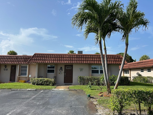 5725 Fernley Dr E Unit 71, West Palm Beach, FL 33415 - view of property featuring uncovered parking, a tile roof, and stucco siding