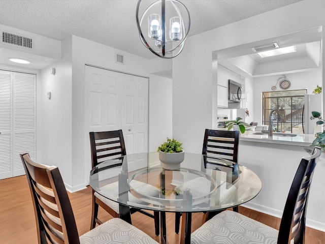 2027 SW 15th St Unit 177, Deerfield Beach, FL 33442 - dining area featuring light wood-style flooring, a chandelier, a textured ceiling, and baseboards