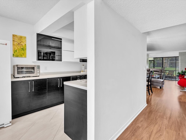 2027 SW 15th St Unit 177, Deerfield Beach, FL 33442 - kitchen with modern cabinets, dark cabinetry, a textured ceiling, light countertops, and light wood-style flooring