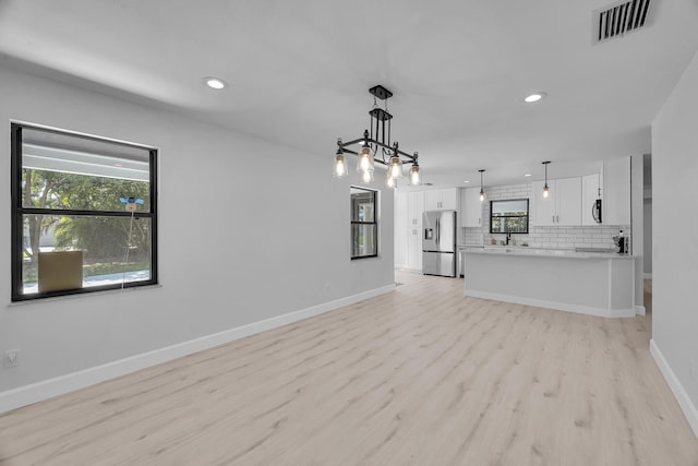 2033 SW Justison Ave, Port Saint Lucie, FL 34953 - unfurnished living room with light wood-type flooring, baseboards, recessed lighting, and a sink