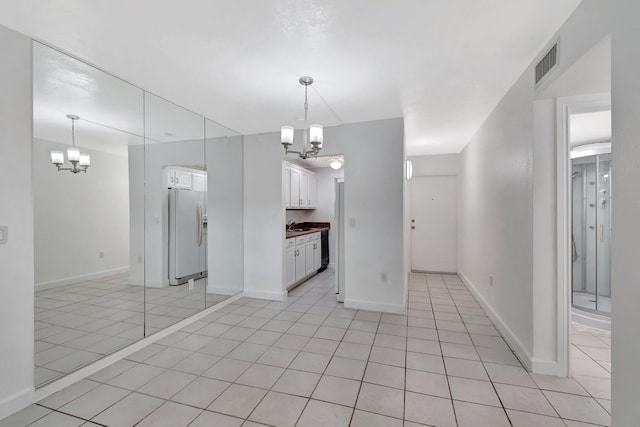 650 SW 2nd Ave Unit 150, Boca Raton, FL 33432 - kitchen featuring a chandelier, white refrigerator with ice dispenser, white cabinetry, and light tile patterned floors