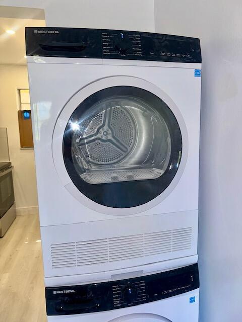 650 SW 2nd Ave Unit 150, Boca Raton, FL 33432 - laundry area featuring stacked washer / dryer, wood finished floors, and baseboards