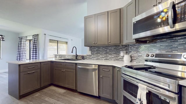 2569 SE Grand Dr, Port Saint Lucie, FL 34952 - kitchen with stainless steel appliances, a sink, a peninsula, decorative backsplash, and light countertops