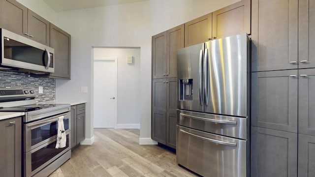 2569 SE Grand Dr, Port Saint Lucie, FL 34952 - kitchen featuring stainless steel appliances, backsplash, light wood-style floors, light countertops, and baseboards