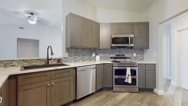 2569 SE Grand Dr, Port Saint Lucie, FL 34952 - kitchen with appliances with stainless steel finishes, a sink, tasteful backsplash, light wood finished floors, and light countertops
