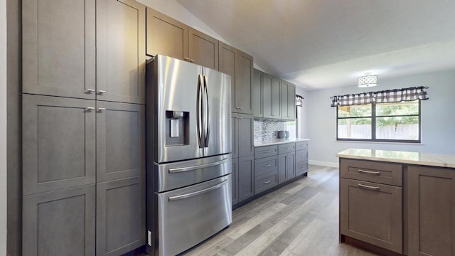 2569 SE Grand Dr, Port Saint Lucie, FL 34952 - kitchen featuring stainless steel fridge with ice dispenser, light wood-type flooring, light countertops, baseboards, and tasteful backsplash