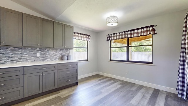 2569 SE Grand Dr, Port Saint Lucie, FL 34952 - kitchen with gray cabinetry, light wood-style floors, tasteful backsplash, baseboards, and light countertops
