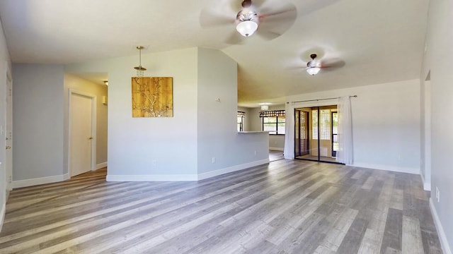 2569 SE Grand Dr, Port Saint Lucie, FL 34952 - unfurnished living room featuring a ceiling fan, baseboards, wood finished floors, and vaulted ceiling