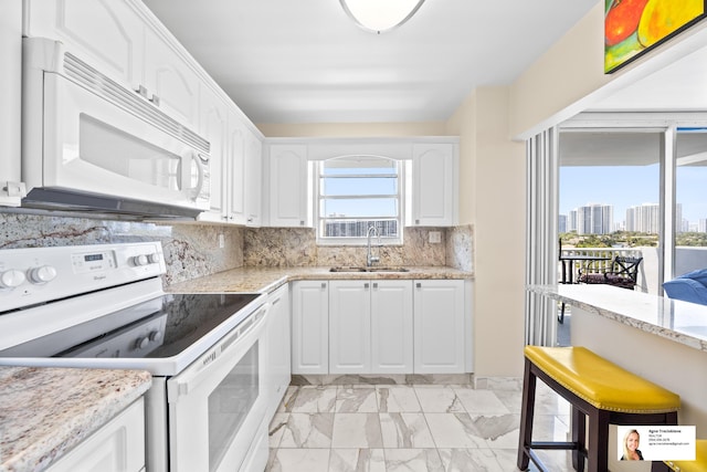 137 Golden Isles Dr Unit 804, Hallandale Beach, FL 33009 - kitchen featuring white appliances, a sink, light marble finish floors, white cabinets, and decorative backsplash