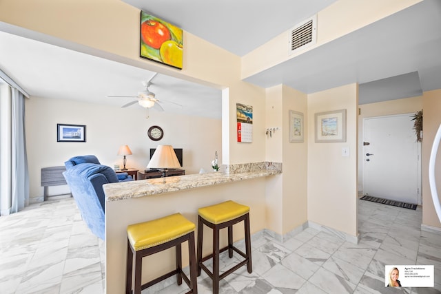137 Golden Isles Dr Unit 804, Hallandale Beach, FL 33009 - kitchen with light marble finish floors, a kitchen breakfast bar, a ceiling fan, a peninsula, and baseboards