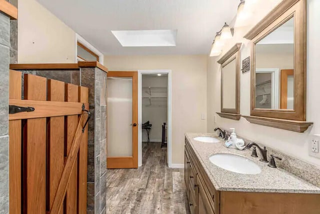 2550 SE Calais St, Port Saint Lucie, FL 34952 - full bathroom with a skylight, wood finished floors, double vanity, and baseboards