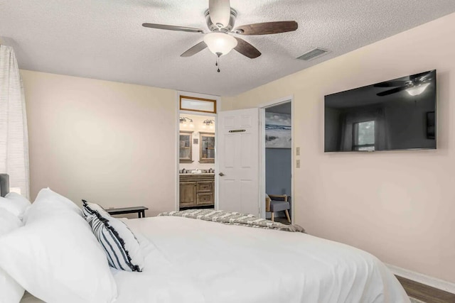 2550 SE Calais St, Port Saint Lucie, FL 34952 - bedroom featuring a textured ceiling, baseboards, a ceiling fan, connected bathroom, and wood finished floors