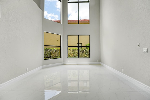 10523 Vignon Ct, Wellington, FL 33449 - empty room with marble look tiles, baseboards, a high ceiling, and a textured wall
