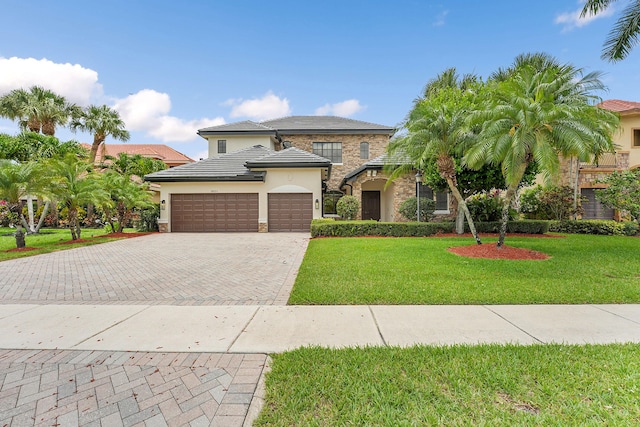 10523 Vignon Ct, Wellington, FL 33449 - view of front of home with stone siding, decorative driveway, an attached garage, stucco siding, and a front yard
