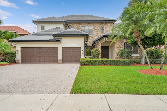 10523 Vignon Ct, Wellington, FL 33449 - view of front of house with stone siding, decorative driveway, an attached garage, a front lawn, and stucco siding