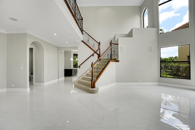 10523 Vignon Ct, Wellington, FL 33449 - stairs featuring arched walkways, marble finish flooring, baseboards, a towering ceiling, and crown molding