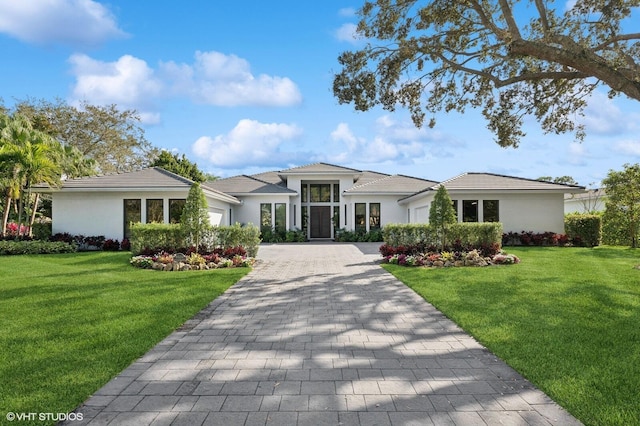 8533 N Native Dancer Rd, Palm Beach Gardens, FL 33418 - prairie-style home with an attached garage, decorative driveway, a front yard, and stucco siding