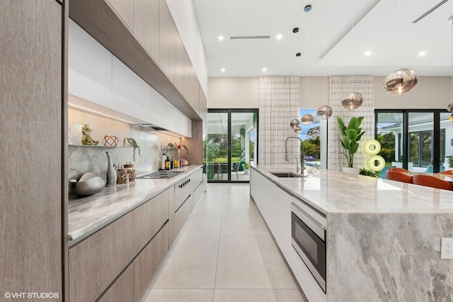 8533 N Native Dancer Rd, Palm Beach Gardens, FL 33418 - kitchen with modern cabinets, a sink, stainless steel microwave, a large island with sink, and stovetop