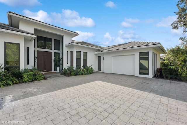 8533 N Native Dancer Rd, Palm Beach Gardens, FL 33418 - view of front facade featuring an attached garage, driveway, stucco siding, and a tiled roof