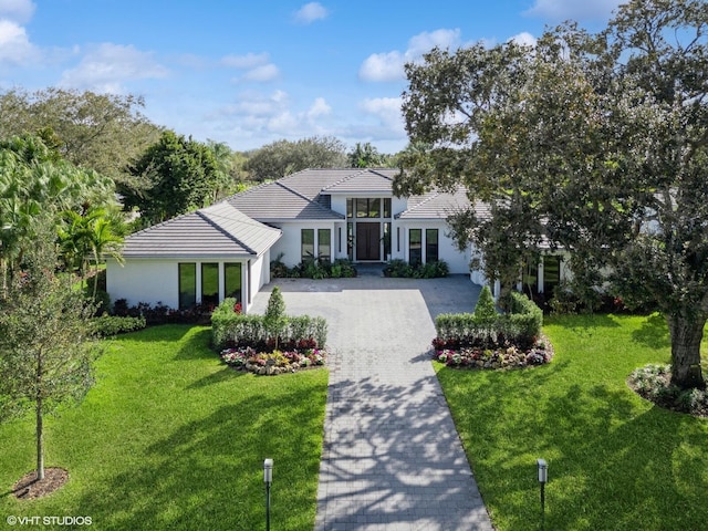 8533 N Native Dancer Rd, Palm Beach Gardens, FL 33418 - view of front of house with decorative driveway, stucco siding, a tile roof, a front yard, and an attached garage