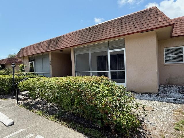 1906 Palmland Dr Unit D, Boynton Beach, FL 33436 - view of property exterior featuring stucco siding, a shingled roof, and mansard roof