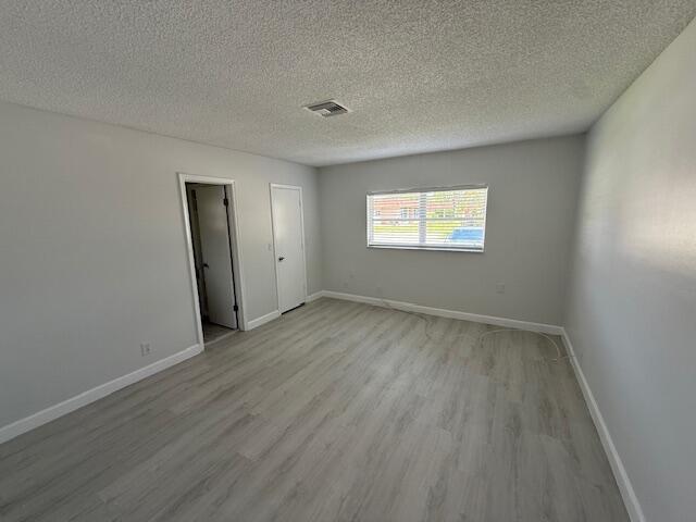1906 Palmland Dr Unit D, Boynton Beach, FL 33436 - unfurnished room with light wood-style flooring, baseboards, and a textured ceiling