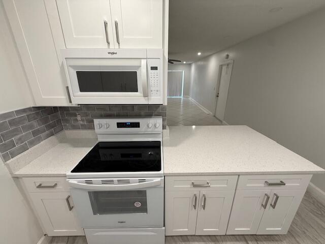 1906 Palmland Dr Unit D, Boynton Beach, FL 33436 - kitchen featuring white appliances, white cabinets, backsplash, light stone counters, and baseboards