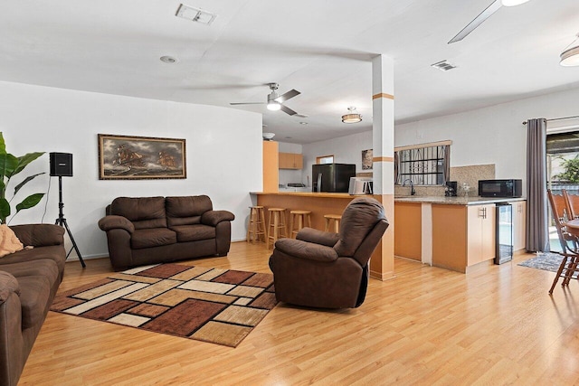 1045 NW 47th Ter, Miami, FL 33127 - living area featuring light wood-style flooring, beverage cooler, and a ceiling fan