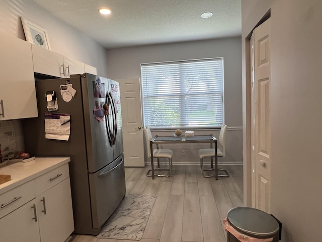 9875 Crescent View Dr S, Boynton Beach, FL 33437 - kitchen with freestanding refrigerator, light wood finished floors, white cabinets, light countertops, and baseboards