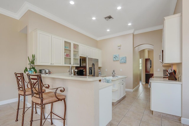 146 Magnolia Way, Tequesta, FL 33469 - kitchen with arched walkways, crown molding, appliances with stainless steel finishes, a peninsula, and light tile patterned floors