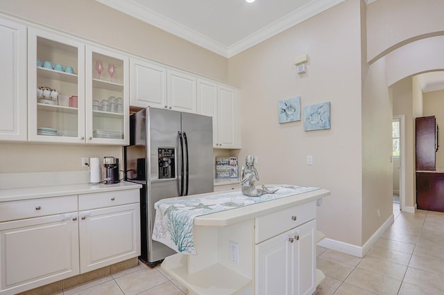 146 Magnolia Way, Tequesta, FL 33469 - kitchen with stainless steel fridge, light countertops, arched walkways, white cabinetry, and light tile patterned floors