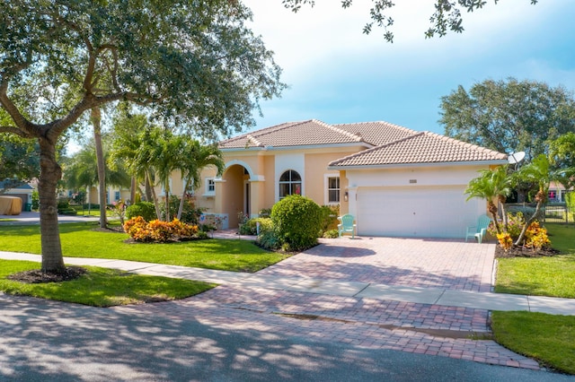 146 Magnolia Way, Tequesta, FL 33469 - mediterranean / spanish-style home featuring an attached garage, decorative driveway, a tiled roof, a front yard, and stucco siding