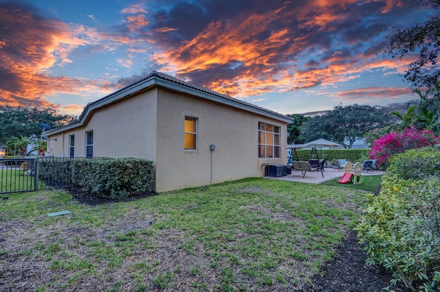 146 Magnolia Way, Tequesta, FL 33469 - property exterior at dusk with a patio, stucco siding, and central air condition unit