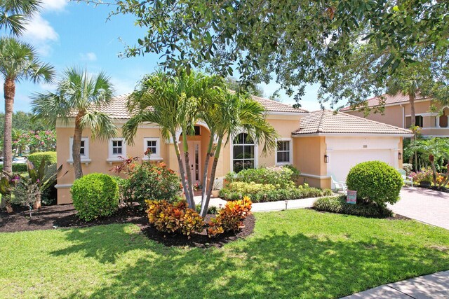 146 Magnolia Way, Tequesta, FL 33469 - mediterranean / spanish home with a garage, a tiled roof, a front yard, stucco siding, and driveway
