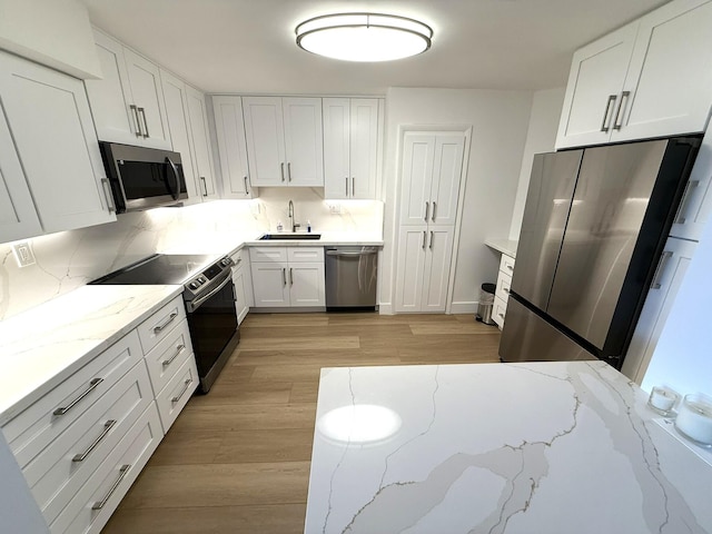 2860 S Ocean Blvd Unit 415, Palm Beach, FL 33480 - kitchen with stainless steel appliances, a sink, white cabinets, light wood-style flooring, and backsplash