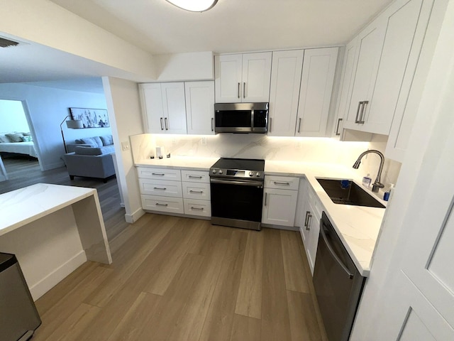 2860 S Ocean Blvd Unit 415, Palm Beach, FL 33480 - kitchen with stainless steel appliances, a sink, light wood finished floors, and white cabinetry
