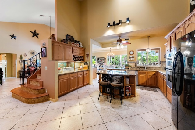 6935 Pioneer Rd, West Palm Beach, FL 33413 - kitchen with freestanding refrigerator, high vaulted ceiling, light stone counters, light tile patterned floors, and a breakfast bar area