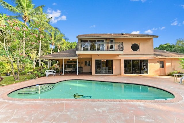 6935 Pioneer Rd, West Palm Beach, FL 33413 - back of house featuring a balcony, stucco siding, a patio area, an outdoor pool, and ceiling fan