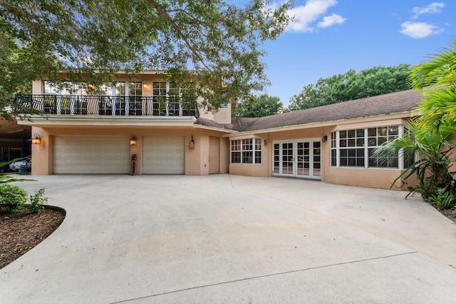 6935 Pioneer Rd, West Palm Beach, FL 33413 - view of front of house with french doors, a balcony, stucco siding, an attached garage, and driveway