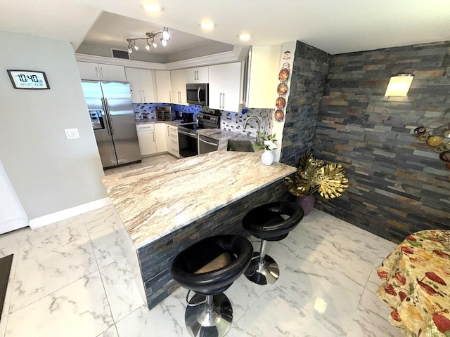 2425 Presidential Way Unit 1804, West Palm Beach, FL 33401 - kitchen with stainless steel appliances, light marble finish flooring, a sink, white cabinets, and a peninsula