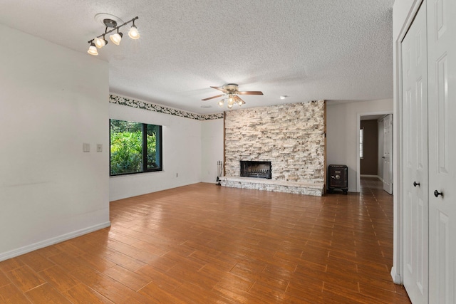 4904 River Pl, Fort Pierce, FL 34982 - unfurnished living room featuring ceiling fan, a textured ceiling, a stone fireplace, wood finished floors, and baseboards