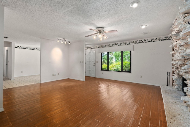4904 River Pl, Fort Pierce, FL 34982 - unfurnished living room with a ceiling fan, wood finished floors, a textured ceiling, rail lighting, and a large fireplace