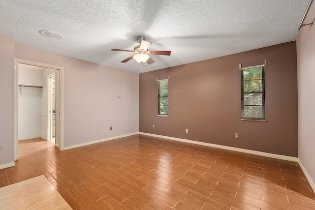 4904 River Pl, Fort Pierce, FL 34982 - unfurnished bedroom with light wood-type flooring, a textured ceiling, baseboards, ceiling fan, and a walk in closet