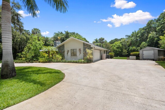4904 River Pl, Fort Pierce, FL 34982 - view of property exterior featuring an outdoor structure, a garage, a lawn, and stone siding