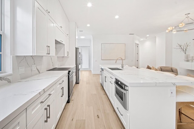 4689 Hammock Cir, Delray Beach, FL 33445 - kitchen featuring a sink, stainless steel appliances, white cabinetry, light wood-style floors, and ornamental molding