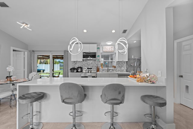 2471 SE Leithgow St, Port Saint Lucie, FL 34952 - kitchen featuring stainless steel appliances, vaulted ceiling, white cabinetry, backsplash, and light countertops