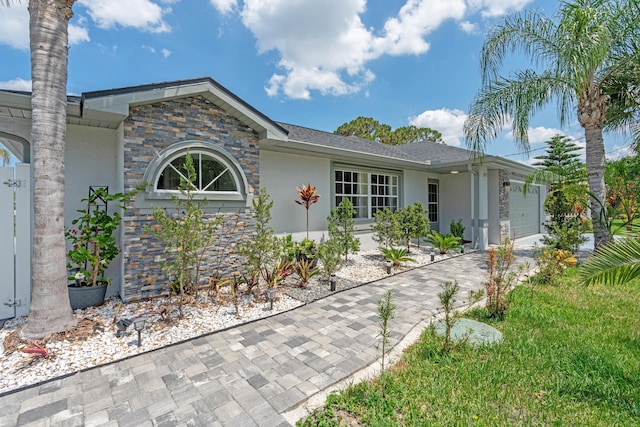 2471 SE Leithgow St, Port Saint Lucie, FL 34952 - ranch-style house featuring stucco siding, a garage, driveway, and stone siding