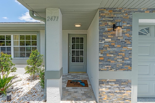 2471 SE Leithgow St, Port Saint Lucie, FL 34952 - view of exterior entry featuring stone siding and stucco siding