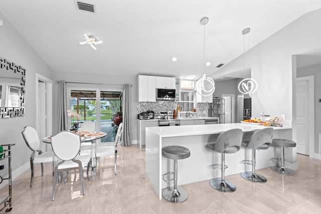 2471 SE Leithgow St, Port Saint Lucie, FL 34952 - kitchen featuring stainless steel appliances, lofted ceiling, a breakfast bar area, light countertops, and a peninsula